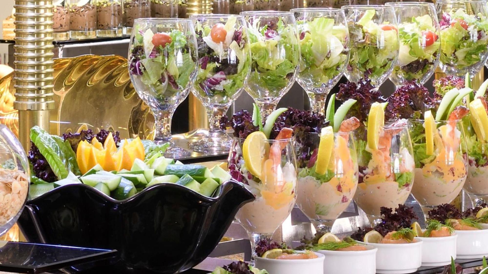 Intercontinental Dar Al Iman Madinah By Ihg Medina Exterior foto The photo features an elegant display of food items. In the background, there are several clear glasses filled with vibrant salads, featuring various types of greens and garnishes. In the foreground, there is a decorative black bowl containing cut pi
