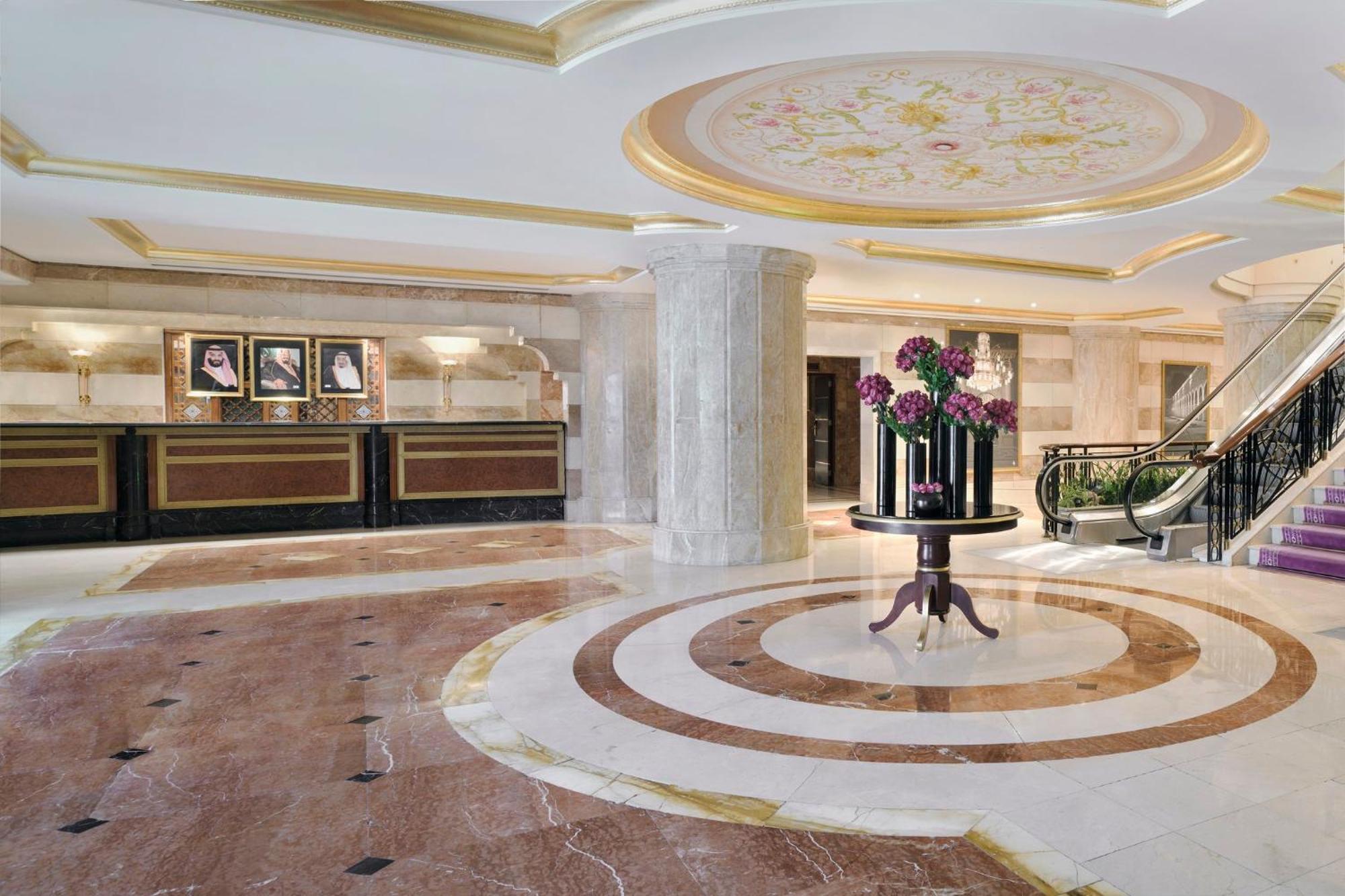 Intercontinental Dar Al Iman Madinah By Ihg Medina Exterior foto The photo shows a luxurious hotel lobby. The space features elegant marble flooring with circular designs, complemented by a large, decorative ceiling. In the center, there is a round table adorned with a floral arrangement. Behind the table, a recep