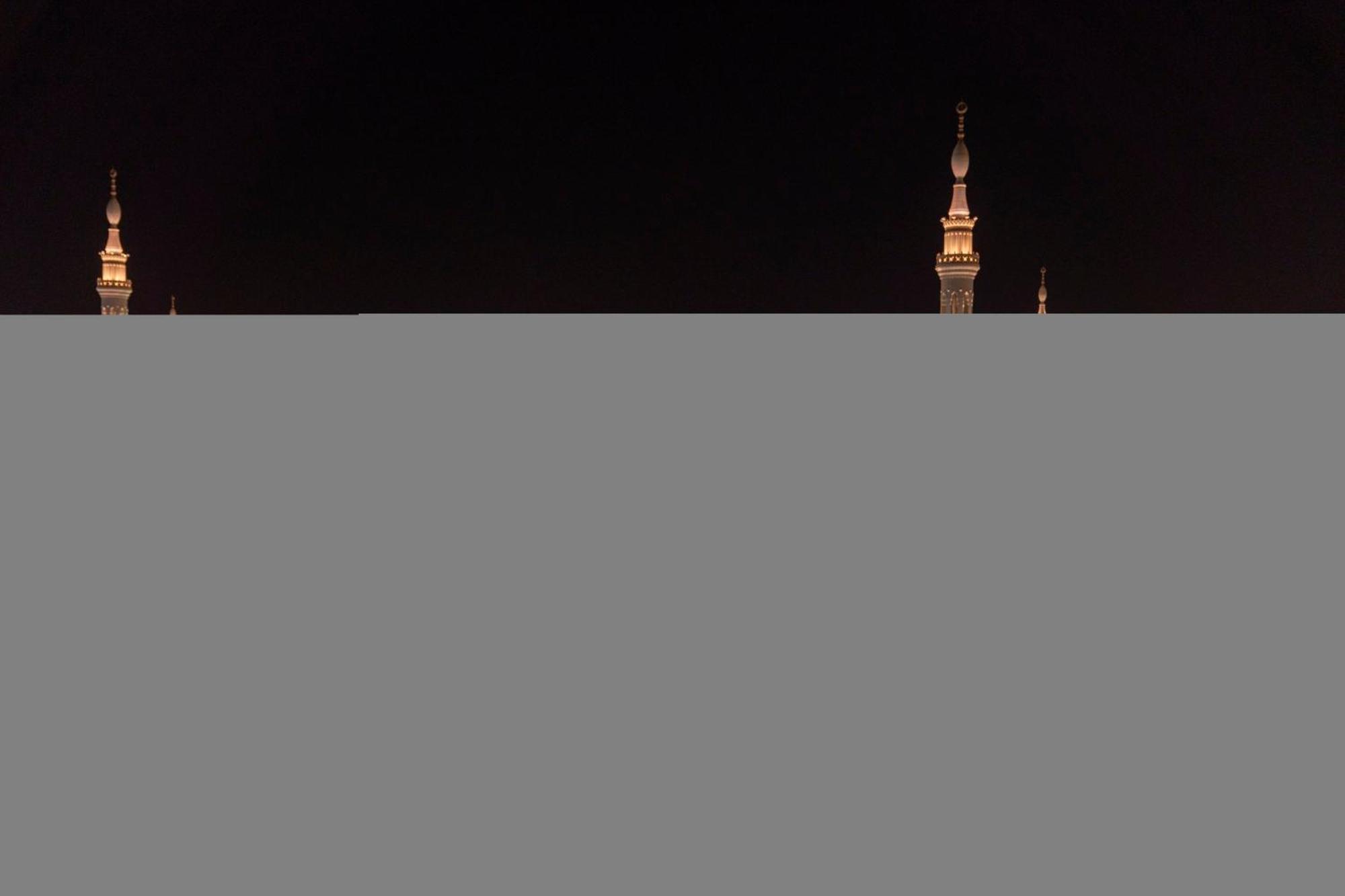 Intercontinental Dar Al Iman Madinah By Ihg Medina Exterior foto The image appears to show a night scene featuring tall structures with pointed tops, likely minarets, illuminated against a dark background. The lighting creates a striking contrast, highlighting the architectural details of the structures. The overa