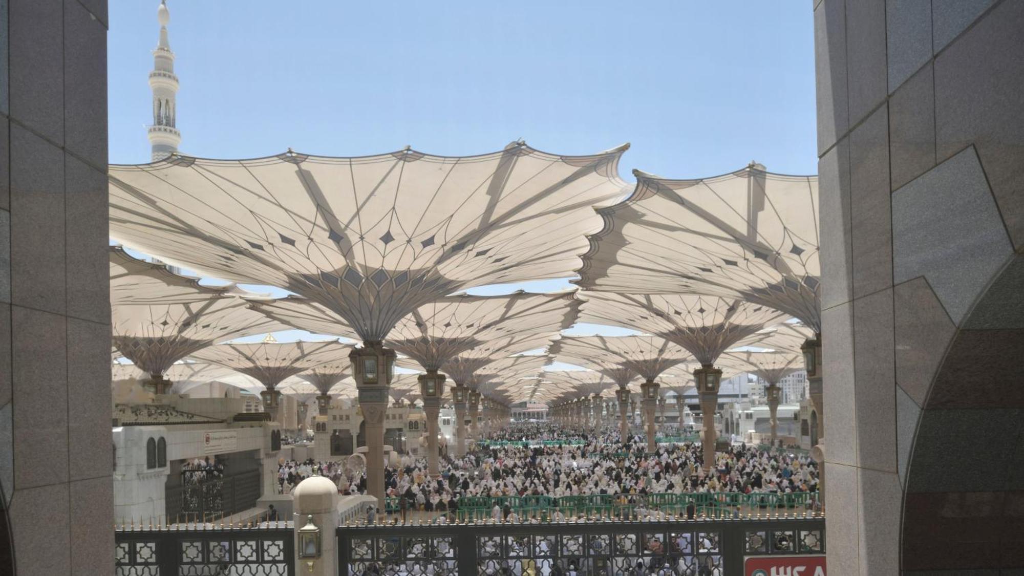 Intercontinental Dar Al Iman Madinah By Ihg Medina Exterior foto The photo shows a large open area covered by expansive canopies, likely designed to provide shade for the people below. Underneath the canopies, there are many individuals gathered, possibly participating in a religious event or gathering. In the bac