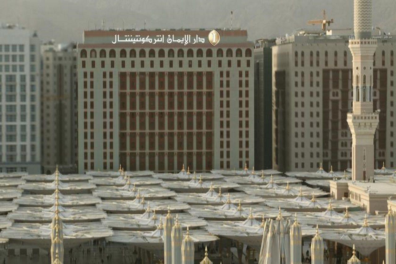 Intercontinental Dar Al Iman Madinah By Ihg Medina Exterior foto The photo shows a view of a large building with a modern architectural design, which appears to be a hotel or a commercial establishment. In front of the building, there are several large white canopies that provide shade, likely in a public space or